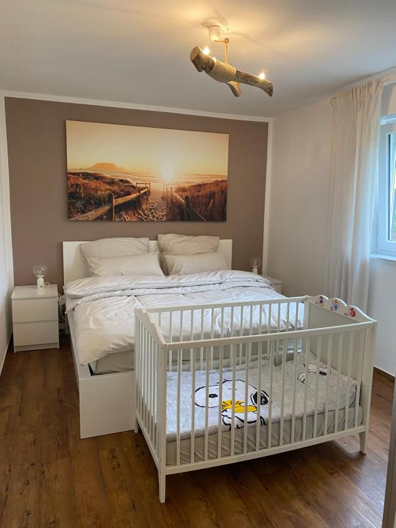 a white crib in a bedroom with a painting on the wall at Ferienwohnung Kilz in Gensingen an der Nahe in Gensingen