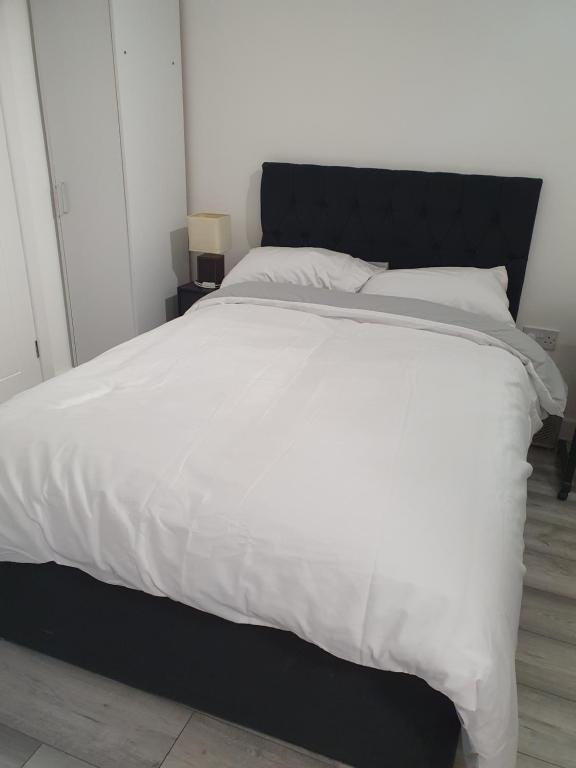 ein großes Bett mit einer schwarzen und weißen Bettdecke in der Unterkunft Glorioushome in Basildon