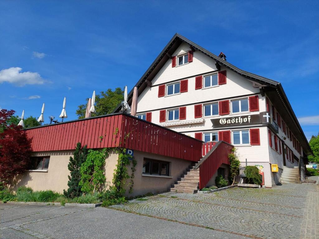 ein großes weißes und rotes Gebäude mit rotem Dach in der Unterkunft Gasthof Kreuz in Bildstein