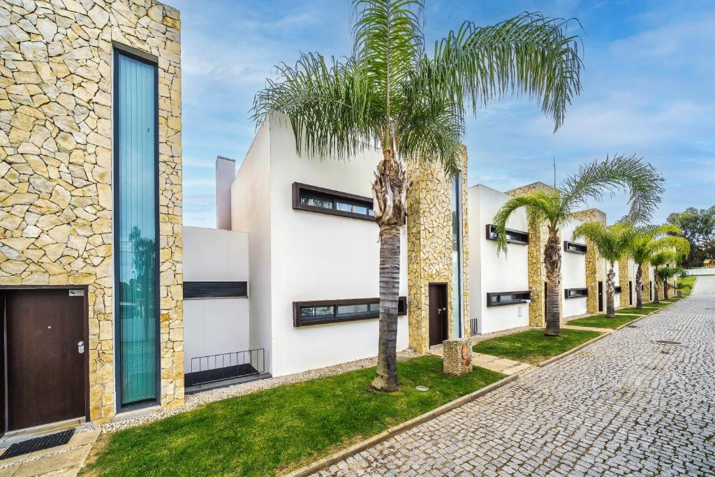 a row of palm trees in front of a building at Modern Luxury Townhouse 3 Bedroom Townhouse Olhos de Agua Communal pool AT03 in Olhos de Água