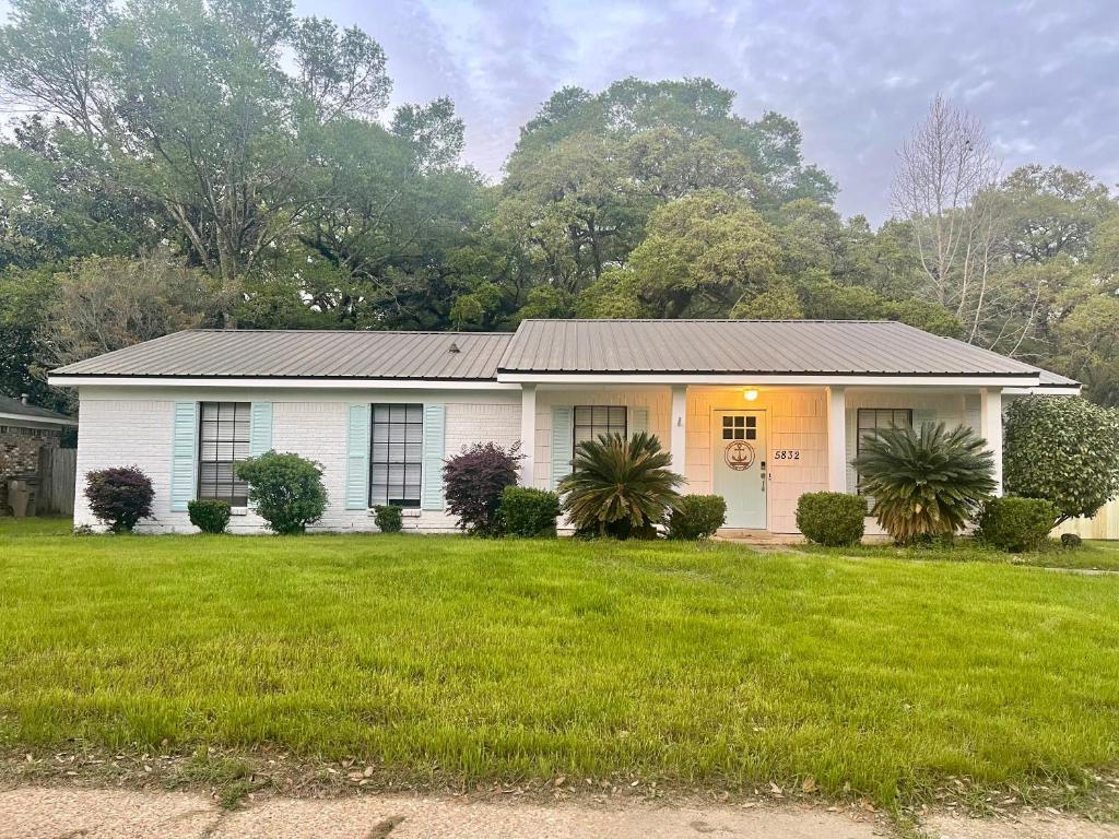 a white house with a grass yard at Cottage Hill Comfort in Mobile
