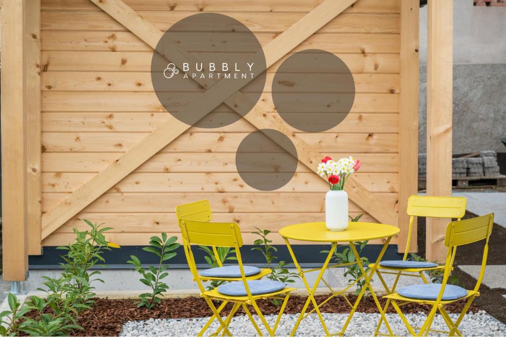 uma mesa amarela e cadeiras em frente a uma parede de madeira em Bubbly Apartment em Bled