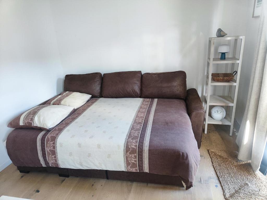 布格奈的住宿－Bienvenu，卧室内的一张床铺,配有棕色皮沙发