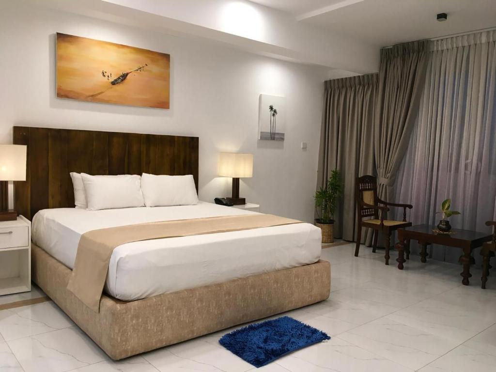 a bedroom with a large bed and a desk at Lavinia Bay Beach Hotel in Mount Lavinia