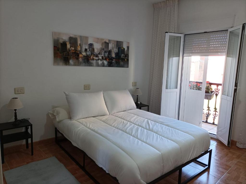 Cette chambre comprend un grand lit blanc et une fenêtre. dans l'établissement Apartamento O Vento, à O Grove