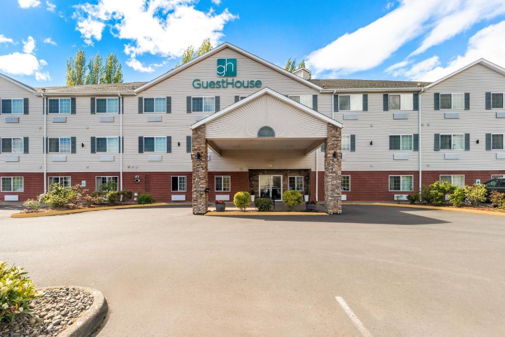 a large white building with a parking lot at GuestHouse Inn & Suites Kelso/Longview in Kelso