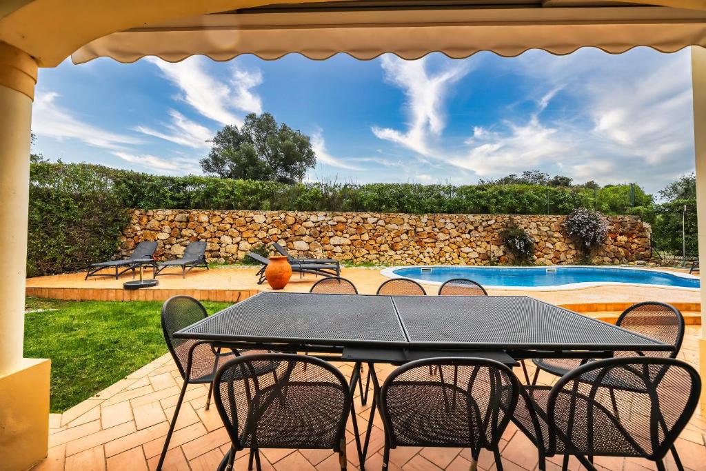 patio ze stołem i krzesłami oraz basenem w obiekcie Luxury 4 bed villa with private pool Oasis Parque, Alvor AT16 w mieście Portimão