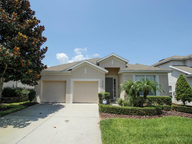 a white house with a garage and a driveway at Comrow Villa 7739 in Orlando