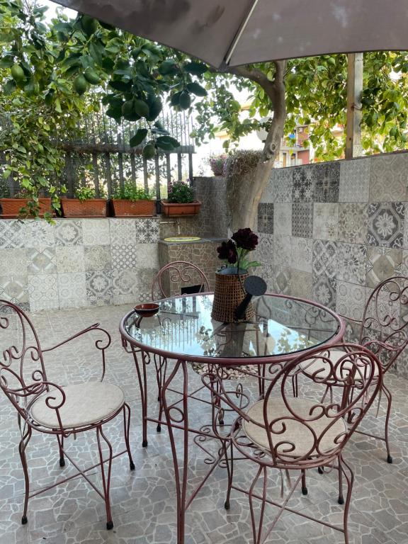 una mesa de cristal y 2 sillas, una mesa y una sombrilla en Appartament casa dei limoni, en Catania