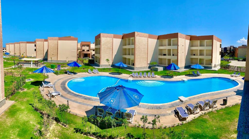una vista aérea de una piscina del complejo con sillas y sombrillas en شاليه فندقى داخل فندق هلنان بورفؤاد Private Apartment Inside Helnan Hotel Port Fouad, en Puerto Saíd
