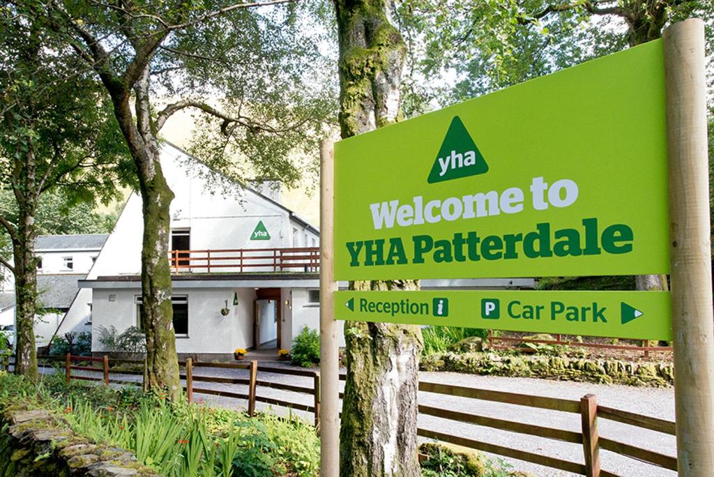 un panneau vert devant un bâtiment dans l'établissement YHA Patterdale, à Glenridding