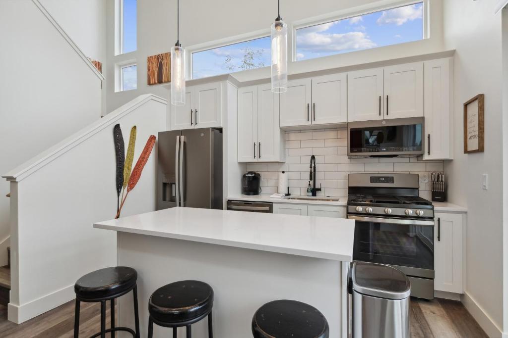 a kitchen with white cabinets and a counter with stools at Quarry A21 in Whitefish