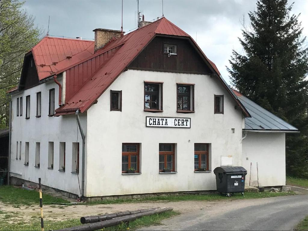 ein altes weißes Gebäude mit rotem Dach in der Unterkunft Chata Čert in Josefův Důl u Jablonce nad Nisou