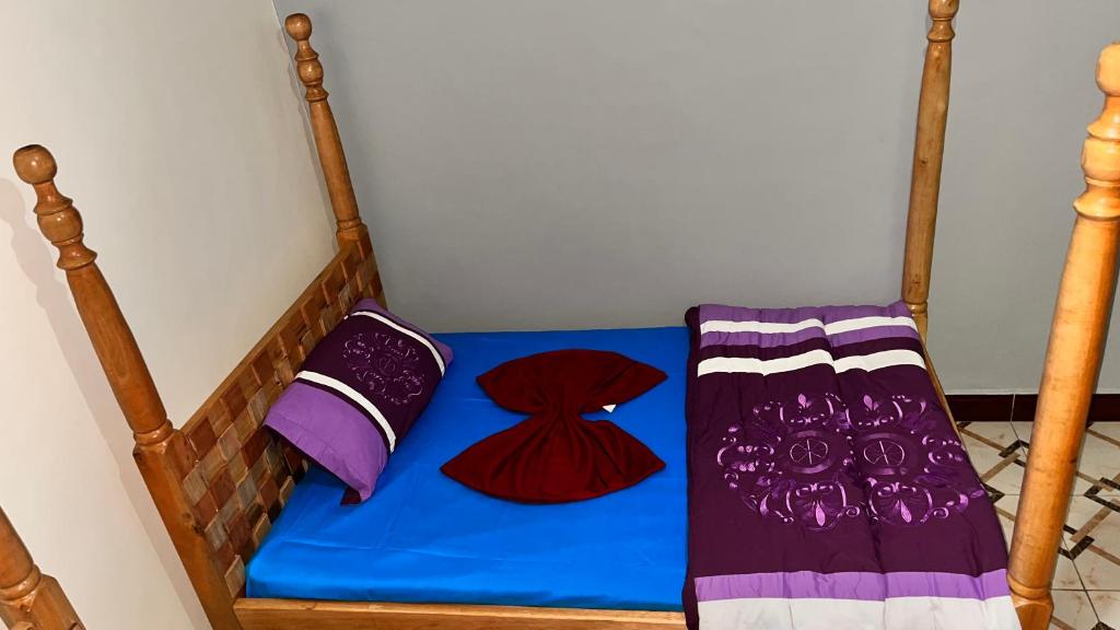 a bed with a blue sheet and two pillows on it at Roots cottages and campsite Ntanda crater lake 