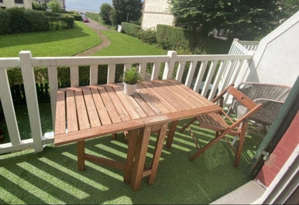 d'une table en bois et d'une chaise sur un balcon. dans l'établissement Le Nid Marin 4 personnes accès direct Plage, à Houlgate