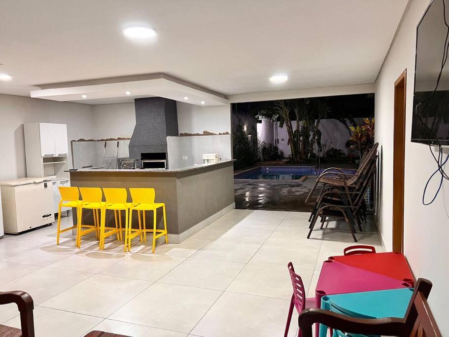 a kitchen with yellow chairs and a kitchen with a pool at Casa em Campo Grande com piscina in Campo Grande