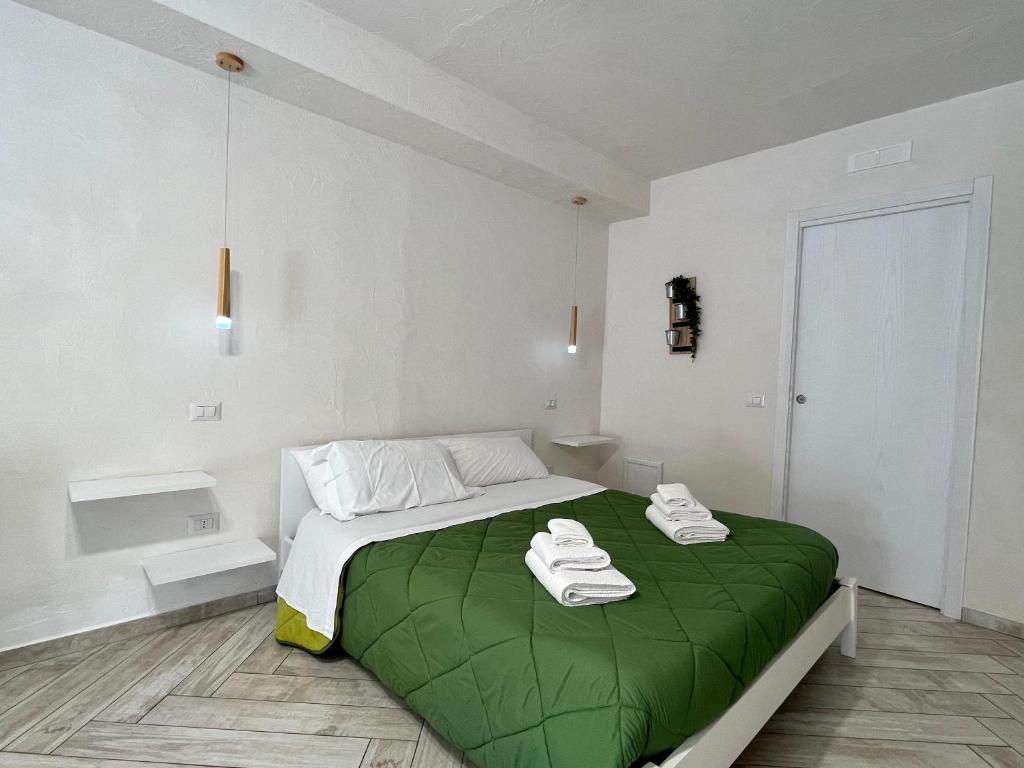 a bedroom with a green bed with two towels on it at B&B Kamalei in Tropea