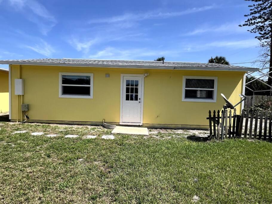 ein gelbes Haus mit einer weißen Tür und einem Zaun in der Unterkunft Beautiful Siesta Key home in Sarasota