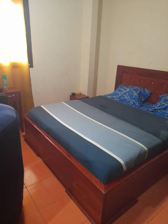 a bed with a wooden frame with a blue mattress at Coubaahala in Yaoundé