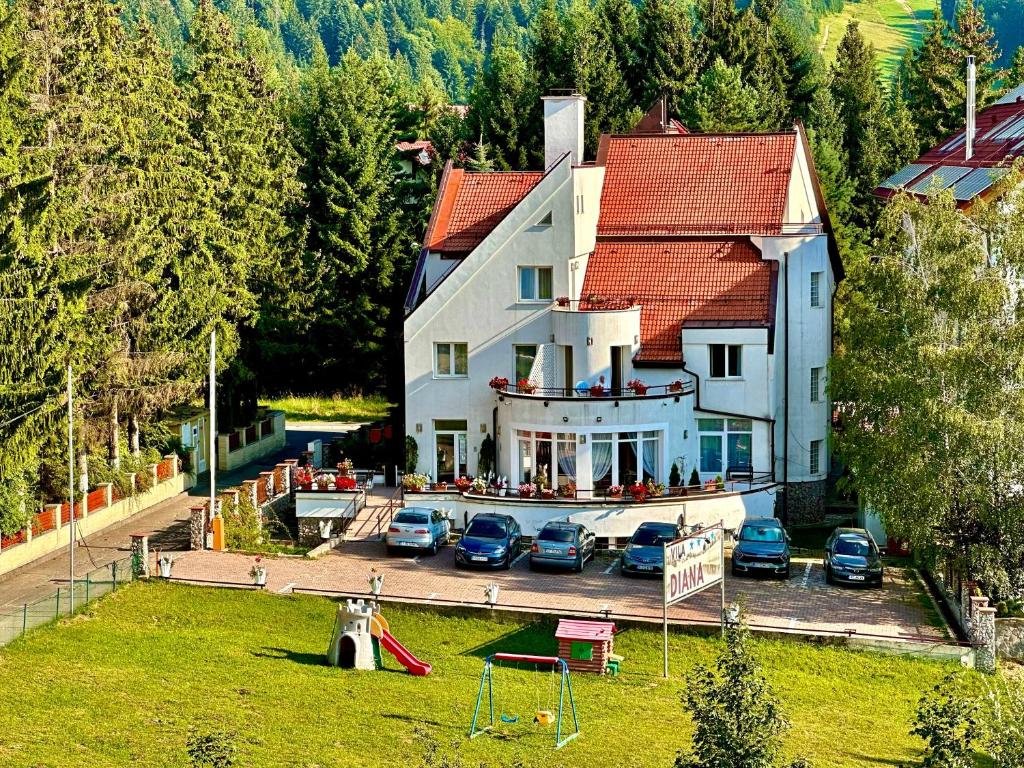 a large house with cars parked in a parking lot at Vila Diana - Poiana Brasov in Poiana Brasov