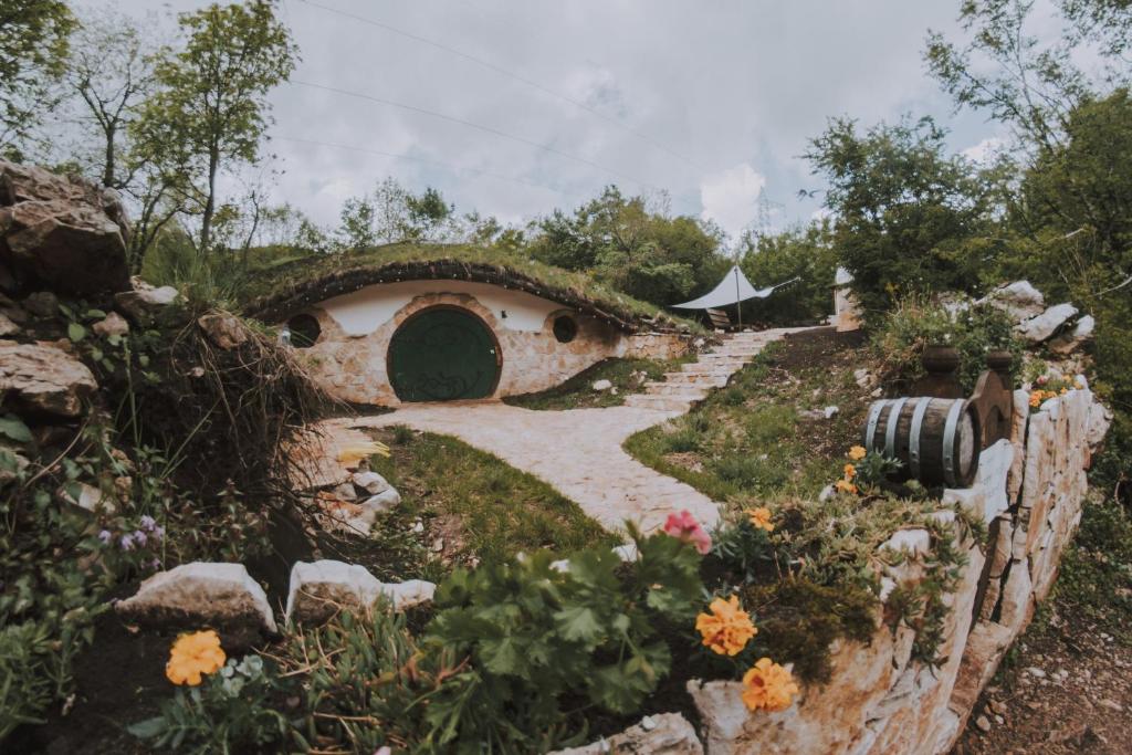 un jardín con un edificio con un camino y flores en Mobbiton Mostar - unique underground stay, en Mostar
