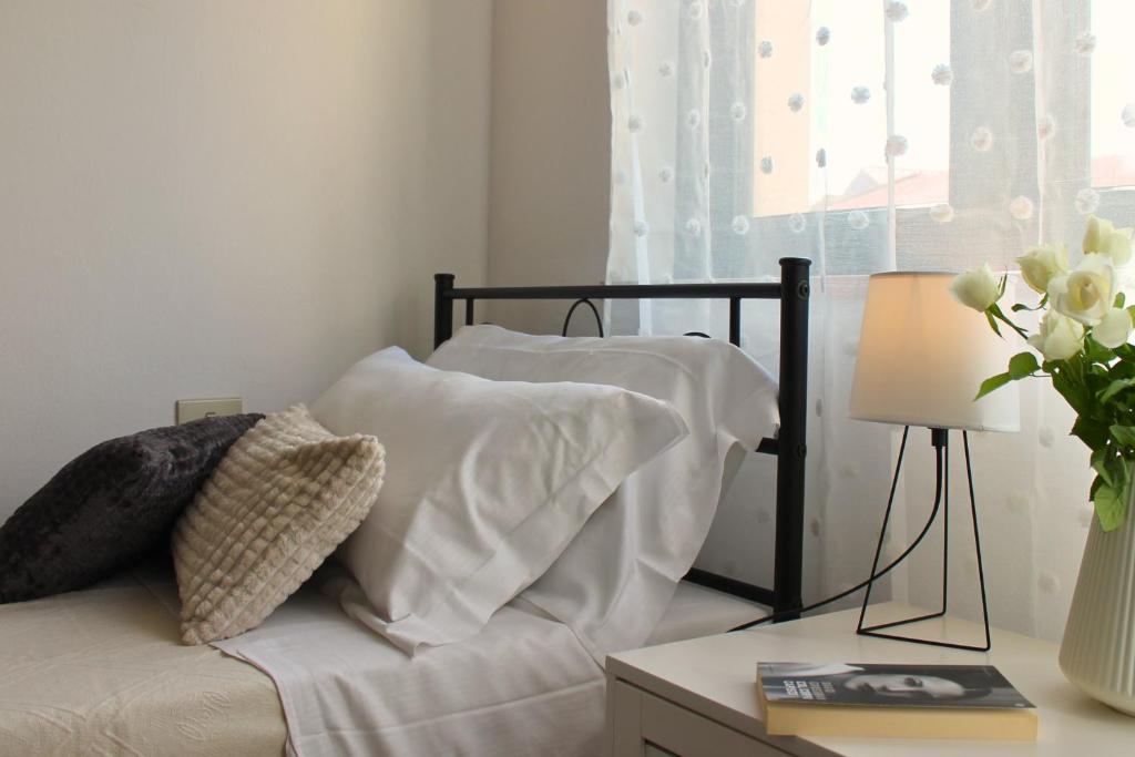 un letto con cuscini bianchi e un tavolo con una lampada di Dimidium Apartment a Guspini