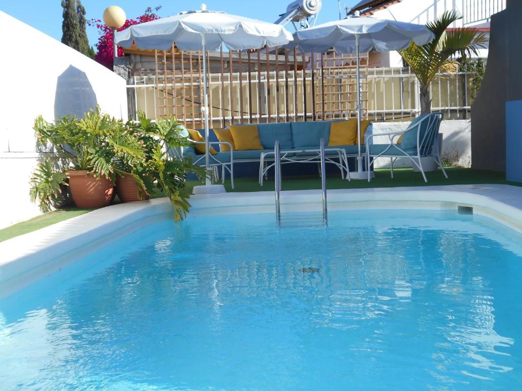 a pool with chairs and umbrellas in a yard at Beach Boys Resort Men Only solo hombres in Maspalomas