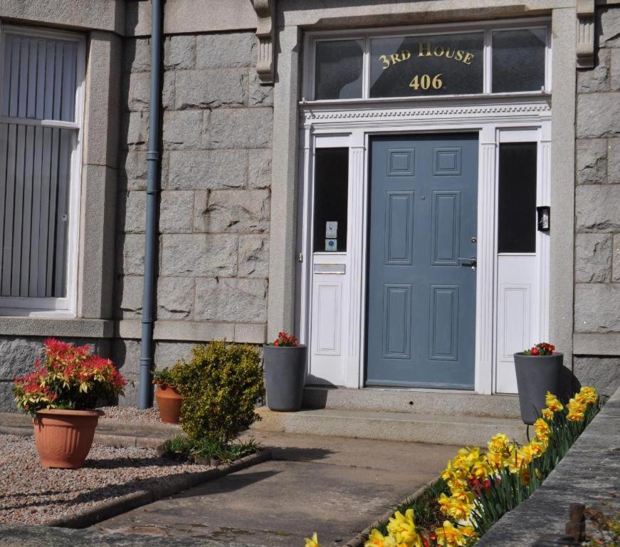 eine blaue Tür an der Seite eines Gebäudes mit Blumen in der Unterkunft Third House Guest House in Aberdeen