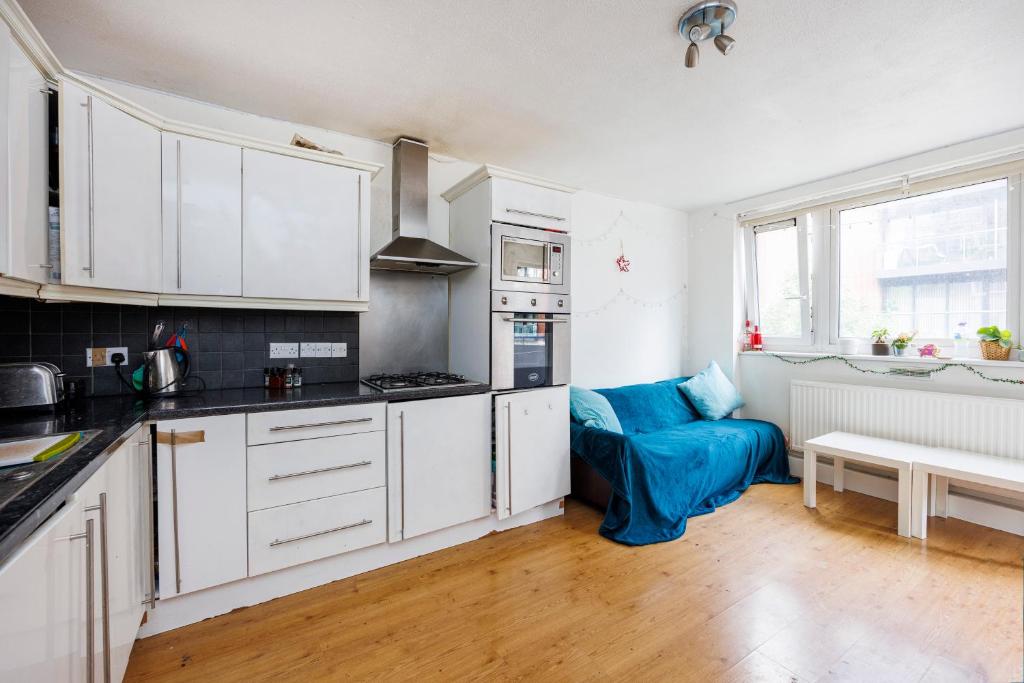 a kitchen with white cabinets and a blue couch at Trendy four bed flat in islington in London