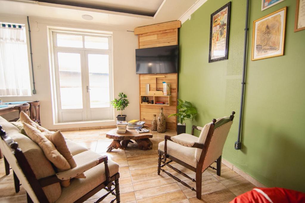 una sala de estar con paredes y sillas verdes y una mesa. en Araucária Hostel e Pousada en São Bento do Sul
