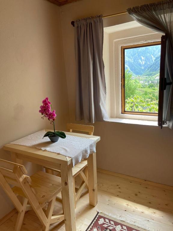 stół z wazonem kwiatów przed oknem w obiekcie Guesthouse "Gjin Thana" w mieście Theth