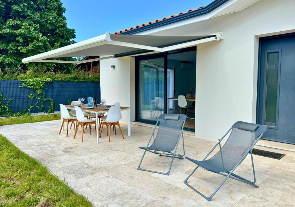d'une terrasse avec des chaises et une table avec un auvent. dans l'établissement Moderne entre lac et océan, à Biscarrosse