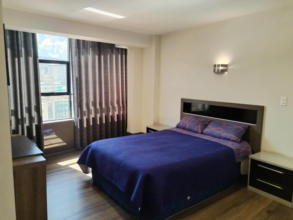 um quarto com uma cama azul e uma grande janela em HOTEL PLATINIUM em La Paz