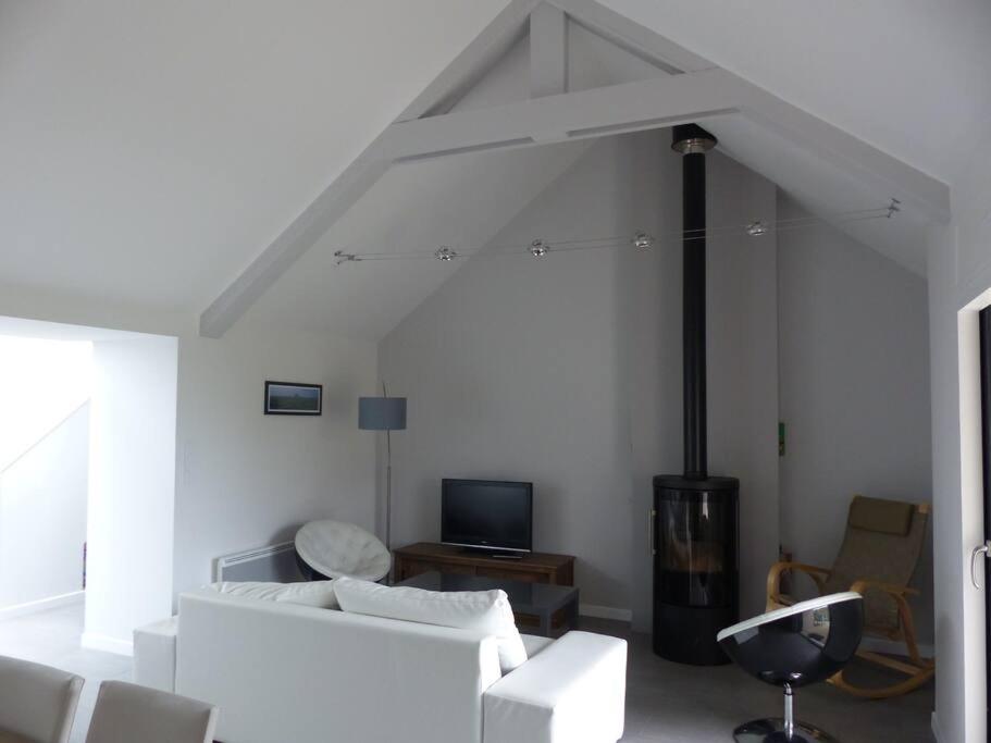 un salon avec un canapé blanc et une télévision dans l'établissement Le 107 grande maison accès direct et vue sur mer, à Cherrueix