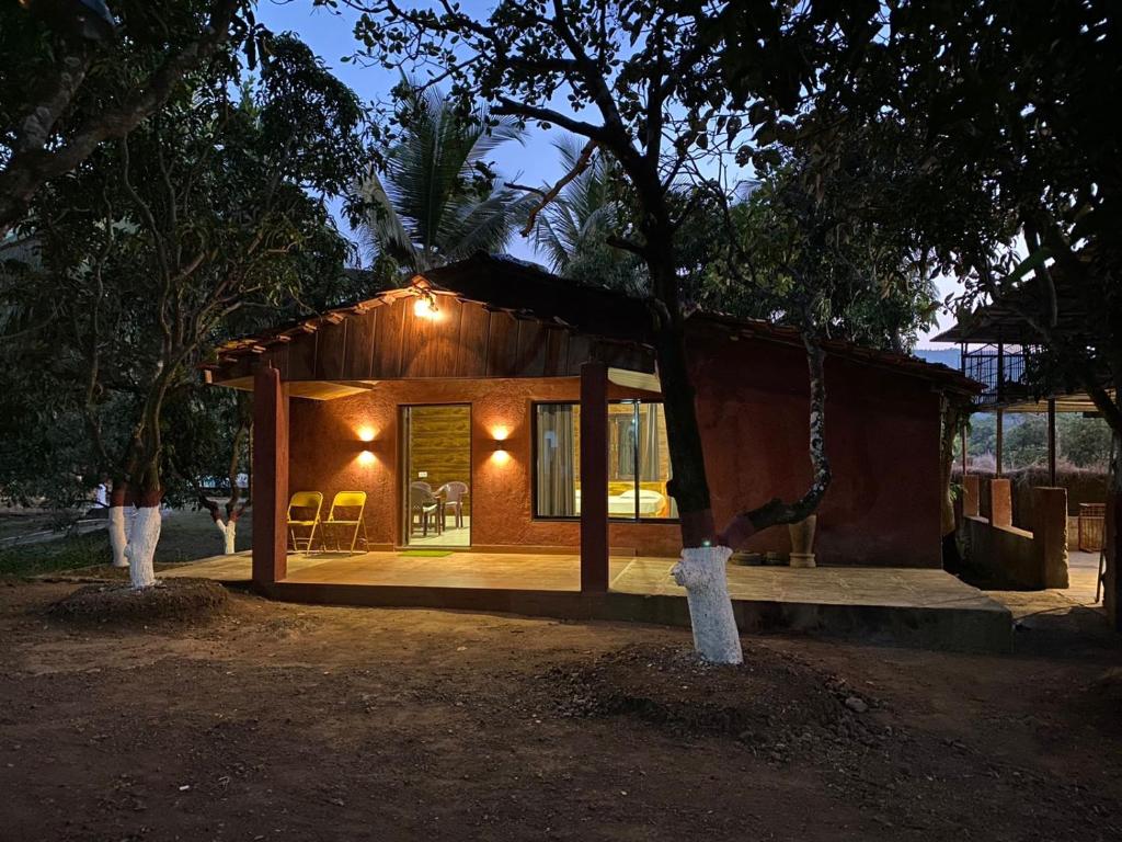 a small house with a porch and a swing at The Mango Woods Cottage with Bathtub in Alibag with Swimming Pool in Alibag