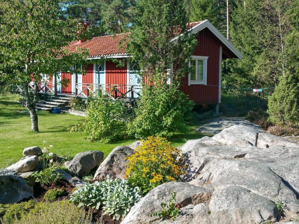 a small red house with rocks in front of it at Holiday home GRÄSÖ II in Gräsö