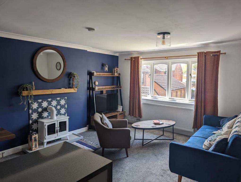 een woonkamer met blauwe muren en een blauwe bank bij Nautical nook, East Yorkshire two bed flat, free parking and WiFi in Hull