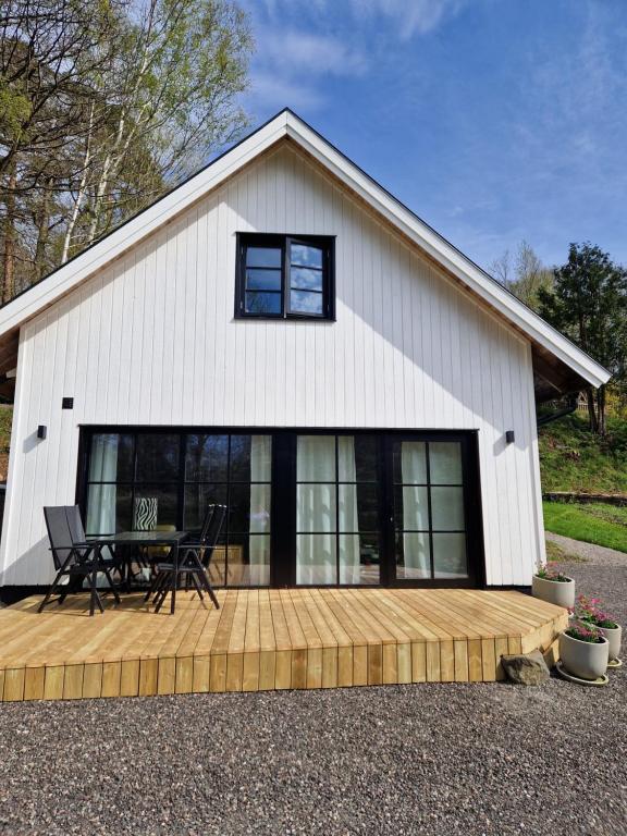 a white barn with a table and chairs on a wooden deck at The little house by the paddock - only for non smokers in Gothenburg