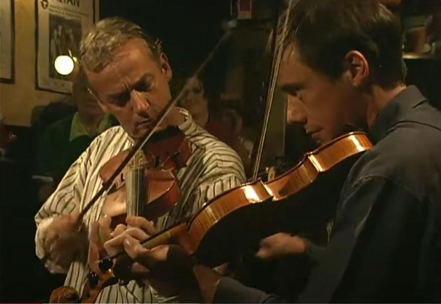 dos hombres tocando violines en una orquesta en Teach Hudí Beag, en Bunbeg