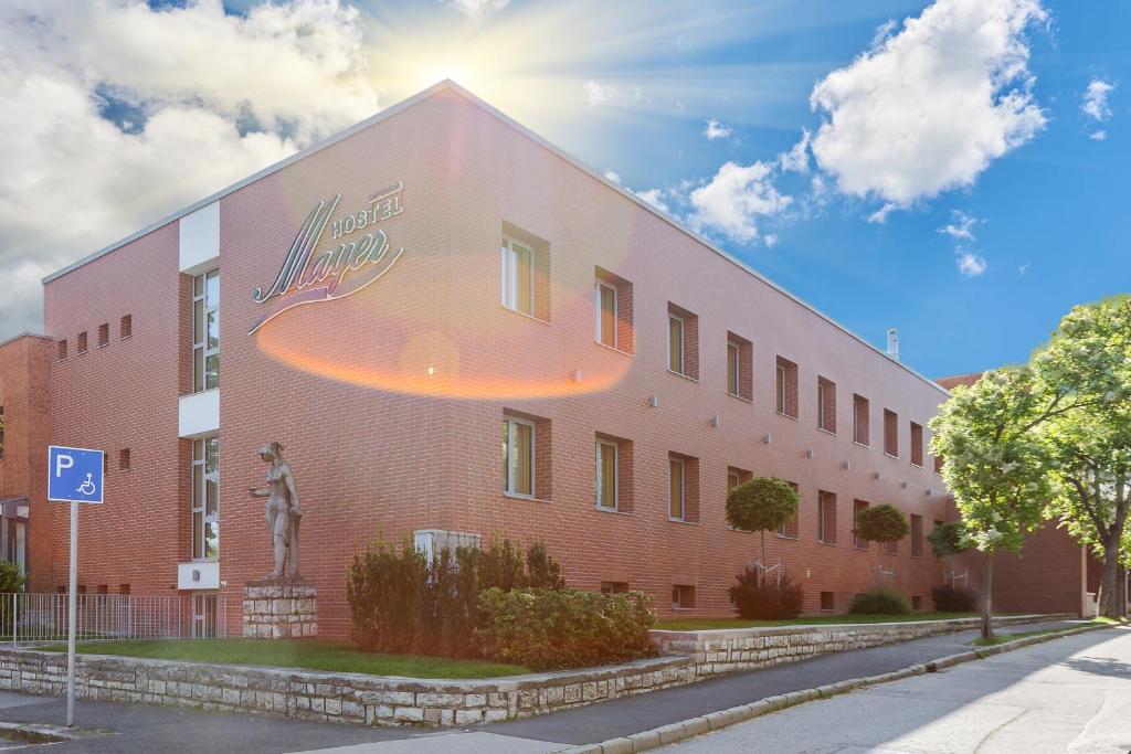 budynek z czerwonej cegły z pomnikiem przed nim w obiekcie Hostel Mayer Superior Veszprém w mieście Veszprém