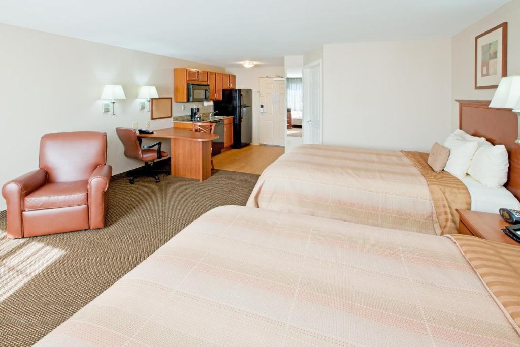 a hotel room with two beds and a chair at Candlewood Suites Lafayette, an IHG Hotel in Lafayette