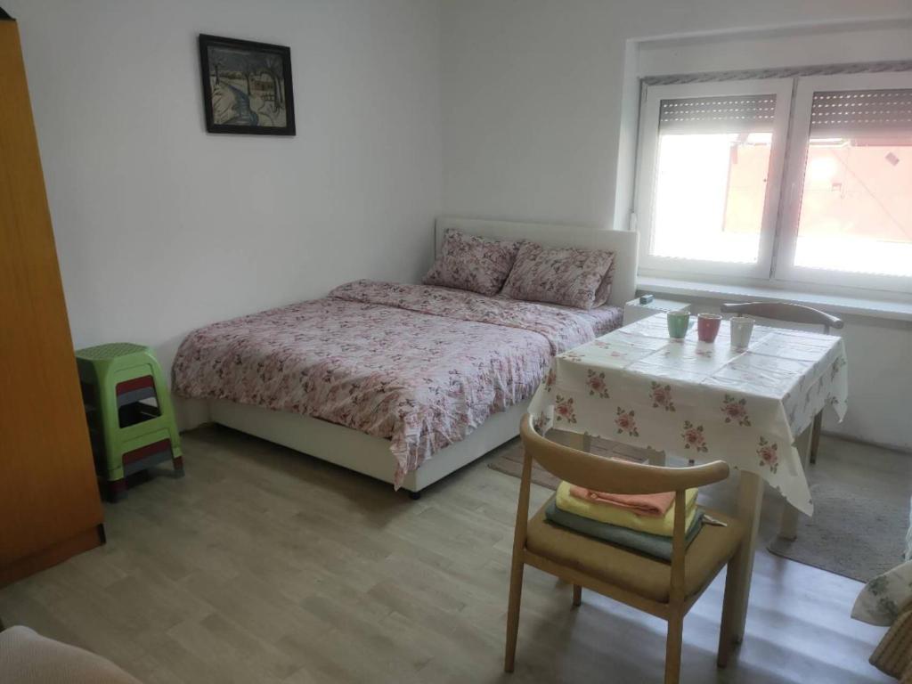a bedroom with a bed and a table and a chair at Cozy hotel with breakfast in Subotica