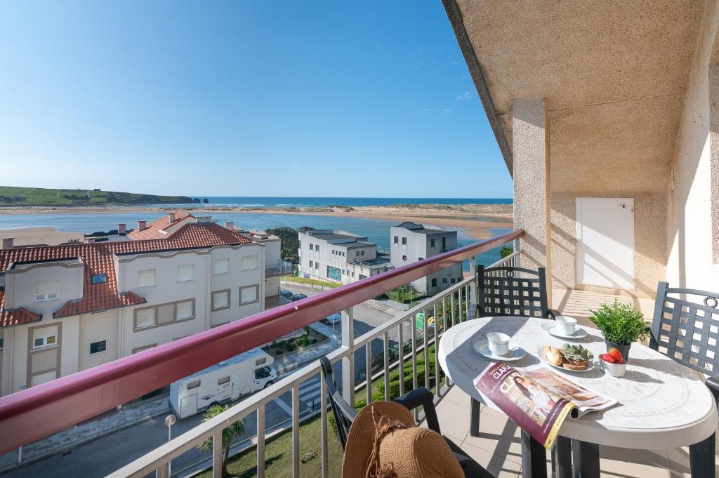 einen Balkon mit einem Tisch und Meerblick in der Unterkunft Apartamento Ría de Mogro in Mogro