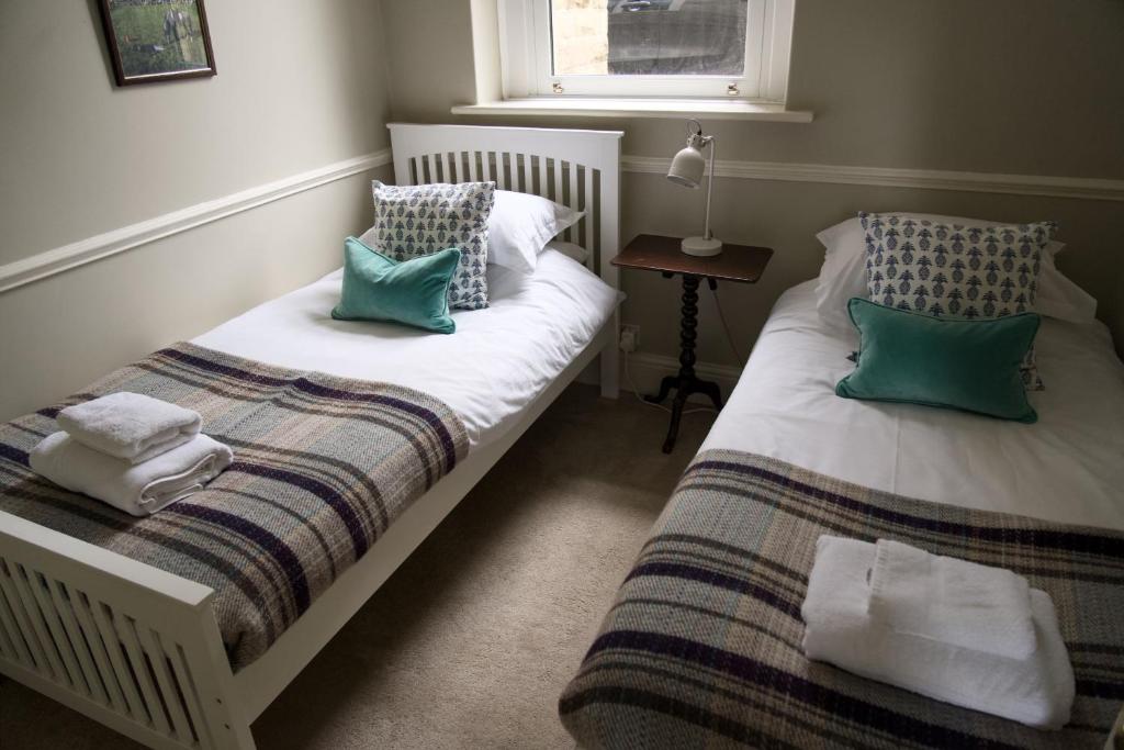 a bedroom with two beds with green and white pillows at The Beeches - Chatsworth Apartment No 2 - Sleeps 4 in Baslow