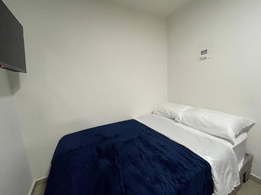 een bed in een witte kamer met een blauwe deken bij Apartaloft en el centro 204 in Pereira
