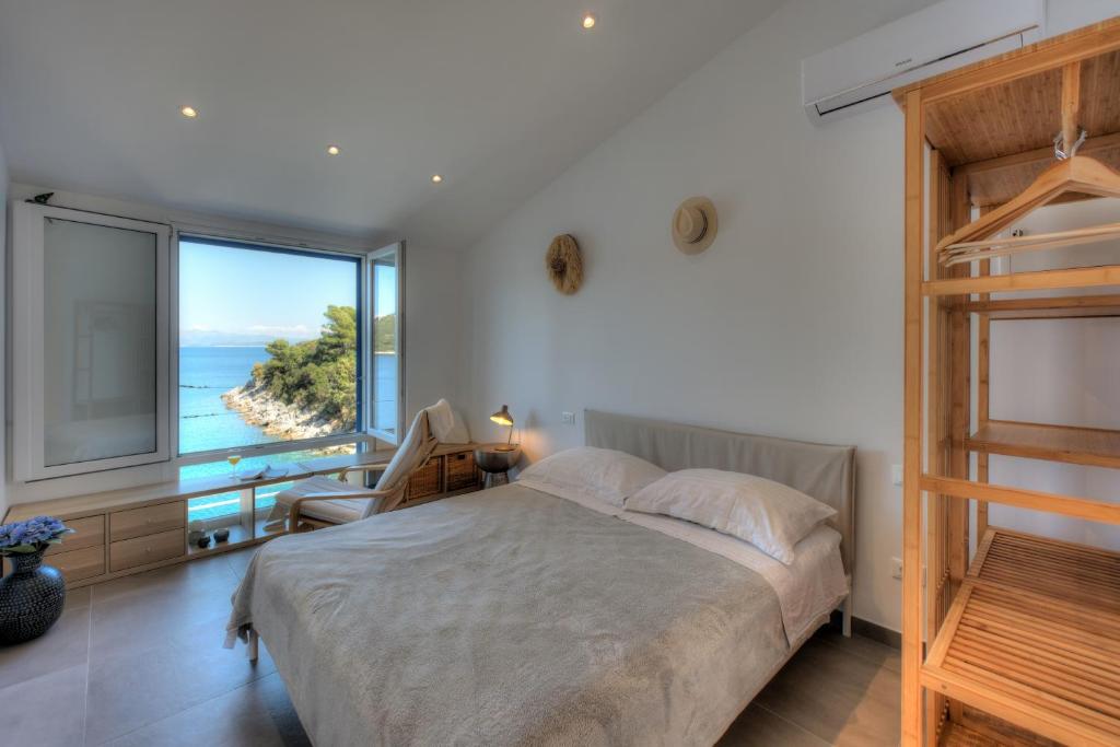 a bedroom with a bed with a view of the ocean at Mljet 4You - Beach House in Sobra