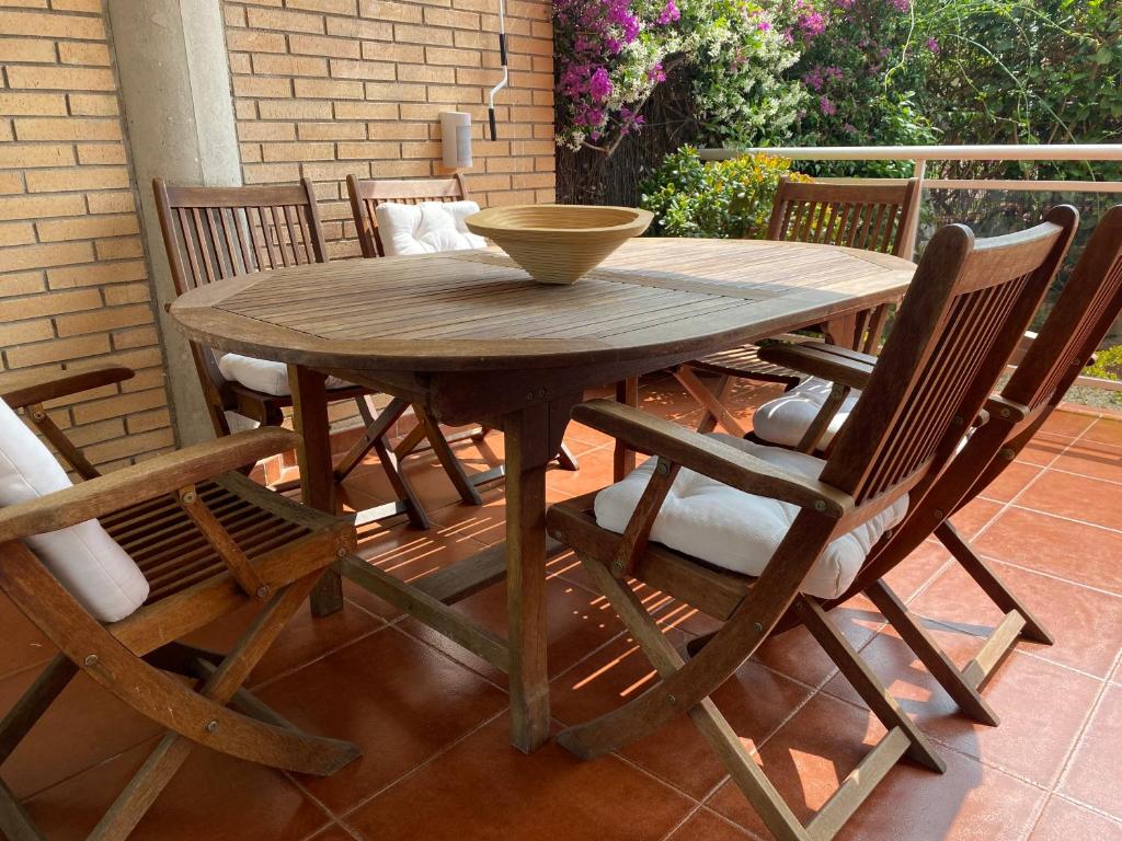 una mesa de madera con sillas y un tazón. en Apartamento 100m2 con piscina y jardín para 6 personas en Cambrils, en Cambrils