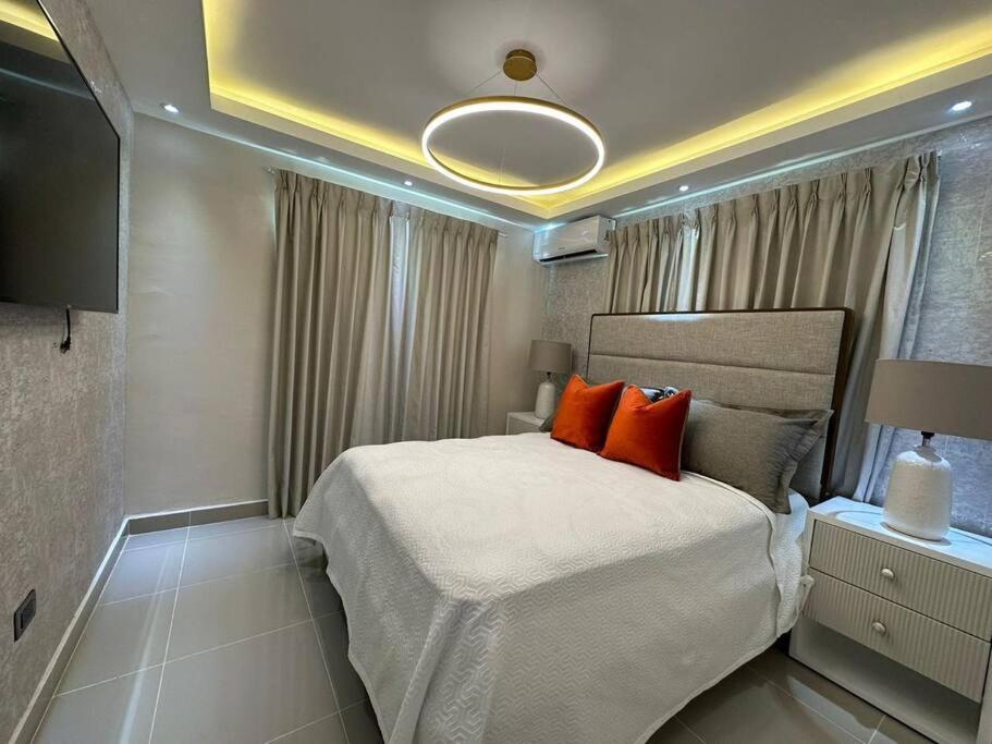 Un dormitorio con una cama grande con almohadas naranjas. en Bienvenido a tu refugió elegante, en Santo Domingo