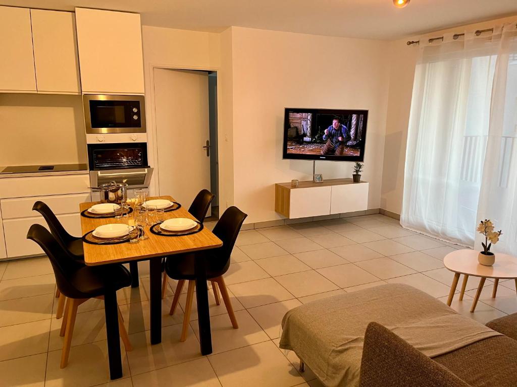 - une cuisine et une salle à manger avec une table et des chaises dans l'établissement Appartement cosy à Bron, à Bron