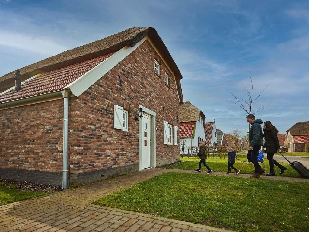 a group of people walking past a brick building at Comfy farmhouse villa in Limburg in Roggel